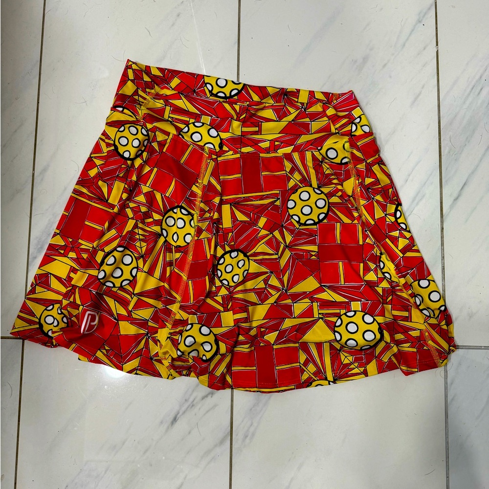 Multicolored pickleball skirt. Orange, yellow, red.  Pickleball motif pattern.